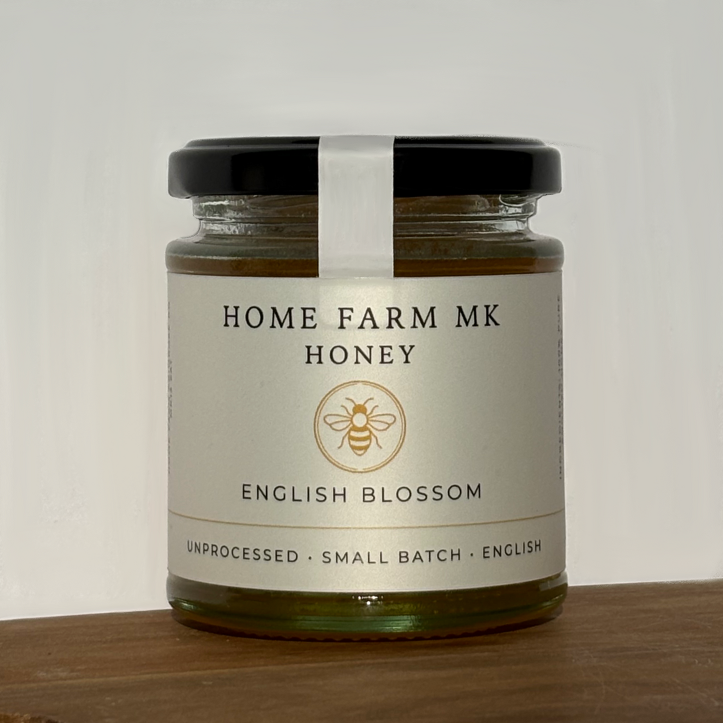 Jar of Home Farm MK Raw English Honey on a wooden surface