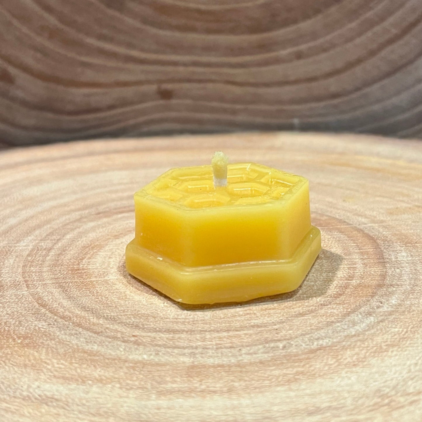 Hexagonal yellow beeswax candle on a wooden surface
