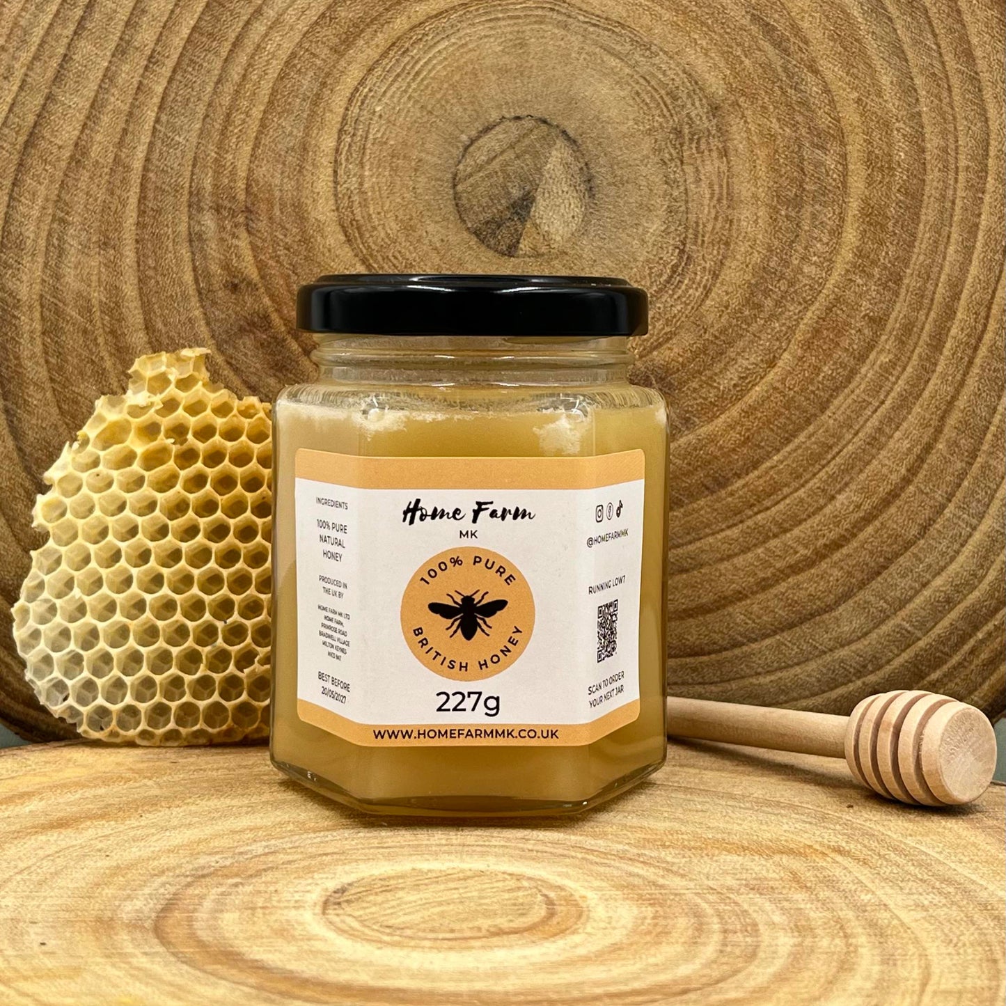 Jar of naturally set honey with a honeycomb and dipper on a wooden background