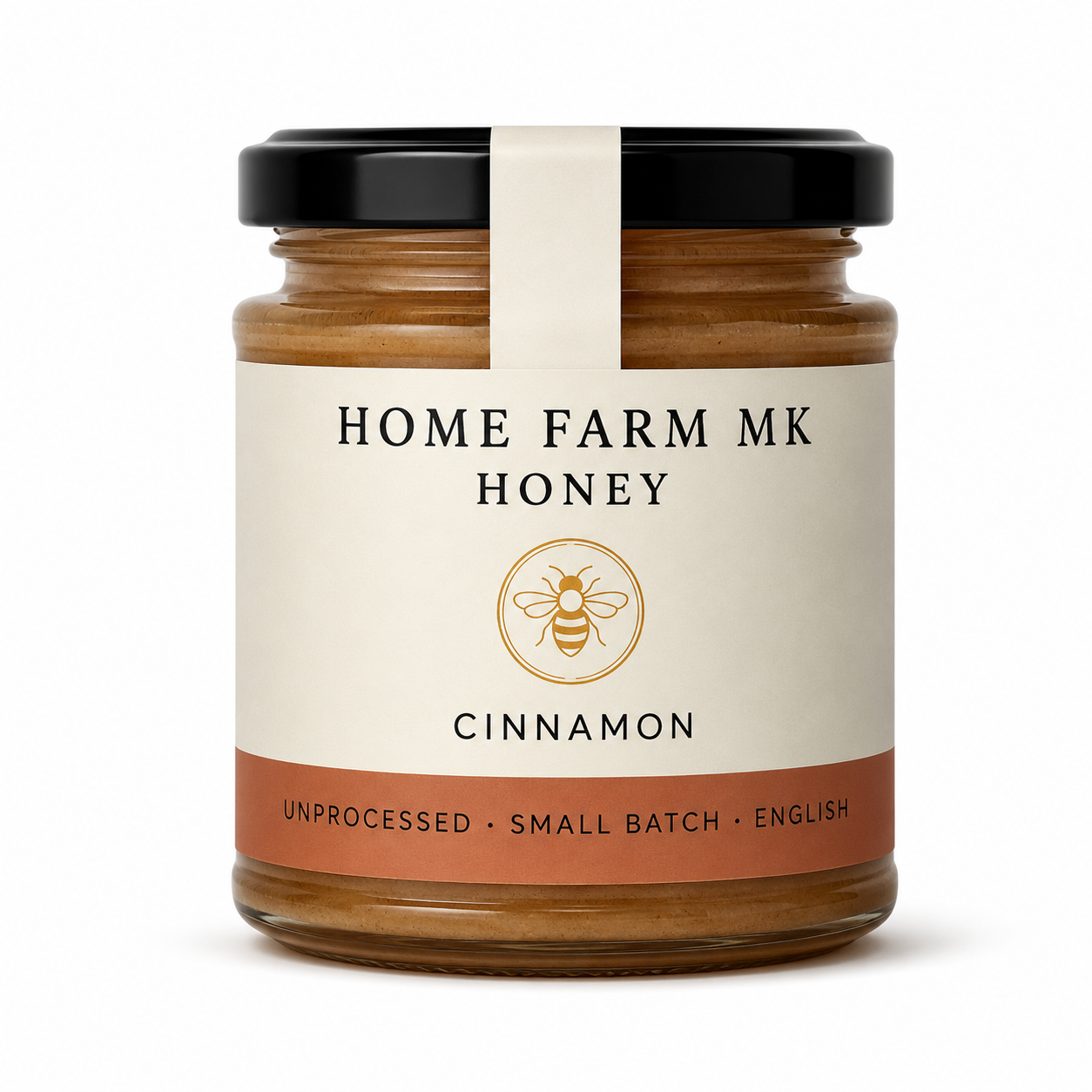 A glass jar of Home Farm Mk Cinnamon Honey with a black lid and a cream-colored label featuring a gold bee logo.