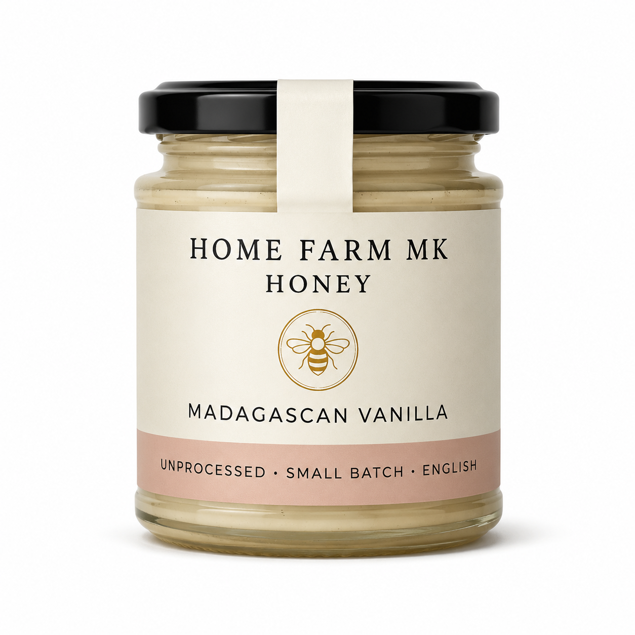 A glass jar of Home Farm MK Honey, Madagascar Vanilla flavor, with a cream-colored label, a black lid, and a white paper band around the neck, set against a plain white background.