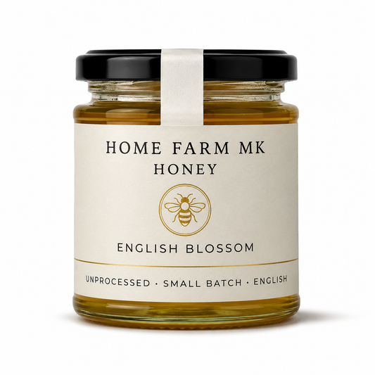 A glass jar of Home Farm Mk English Blossom Honey with a cream-colored label and a black lid, set against a plain white background.