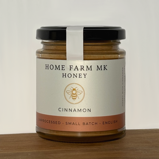 Jar of Home Farm MK Honey with cinnamon on a wooden surface