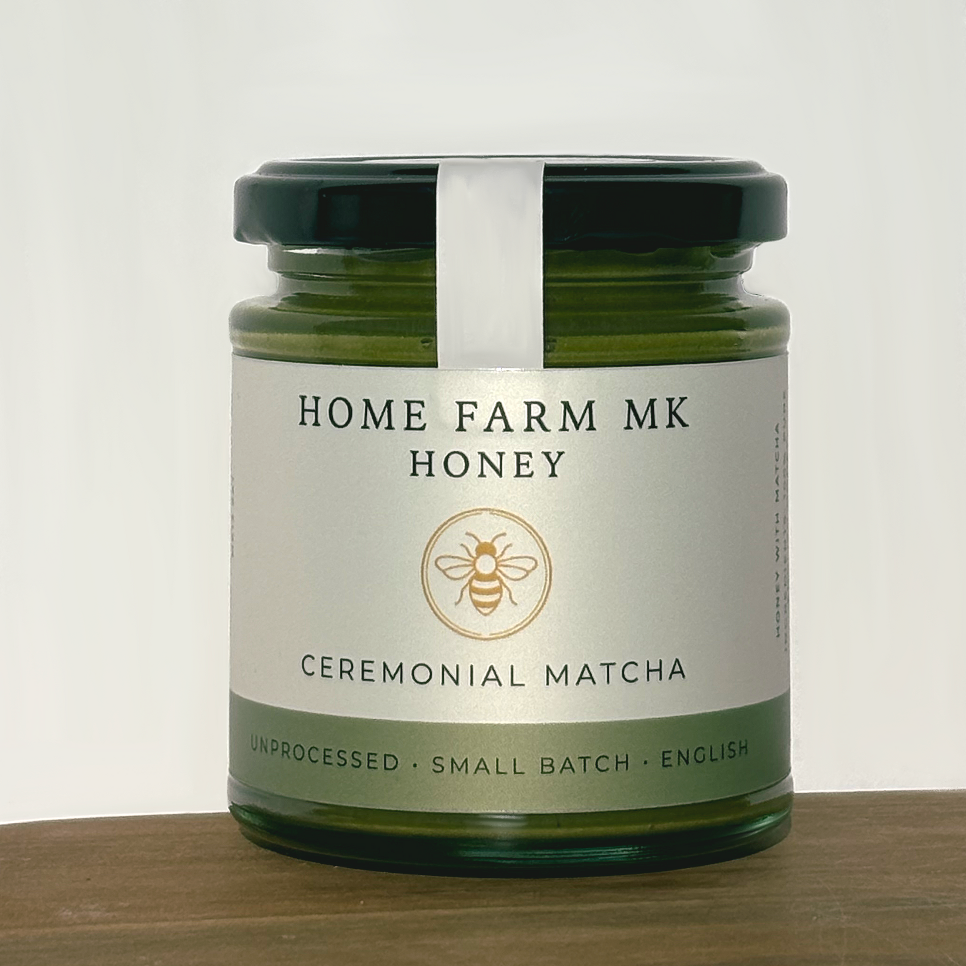 Jar of Home Farm MK Matcha Honey with Ceremonial Grade Matcha on a wooden surface