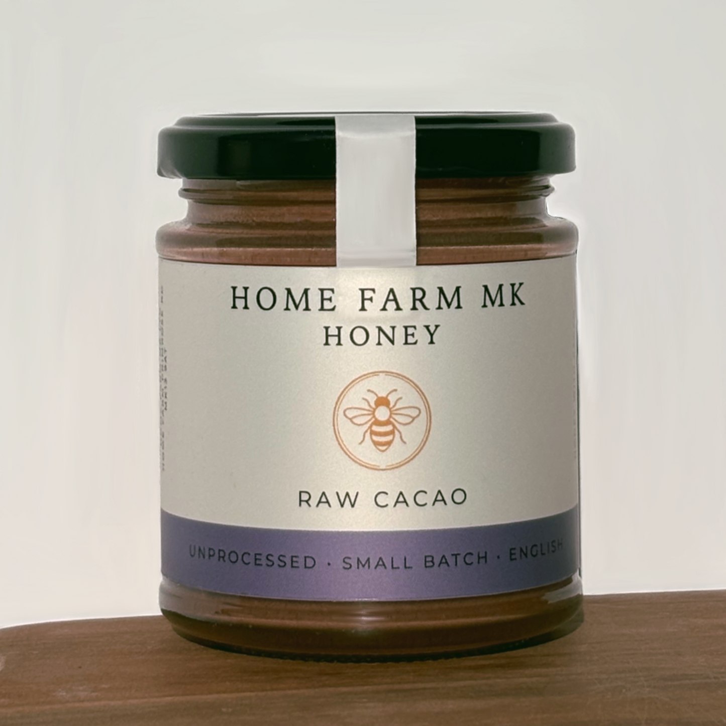Jar of Home Farm MK honey with Raw Cacao on a wooden surface