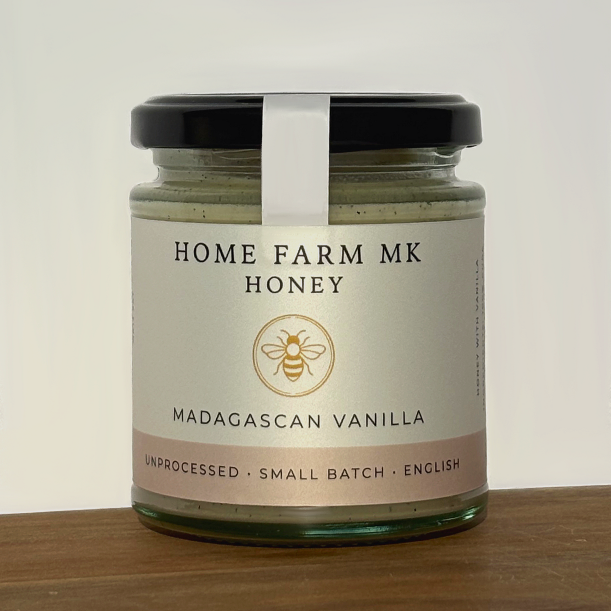 Jar of Home Farm MK Vanilla Honey with Madagascan Vanilla Beans on a wooden surface