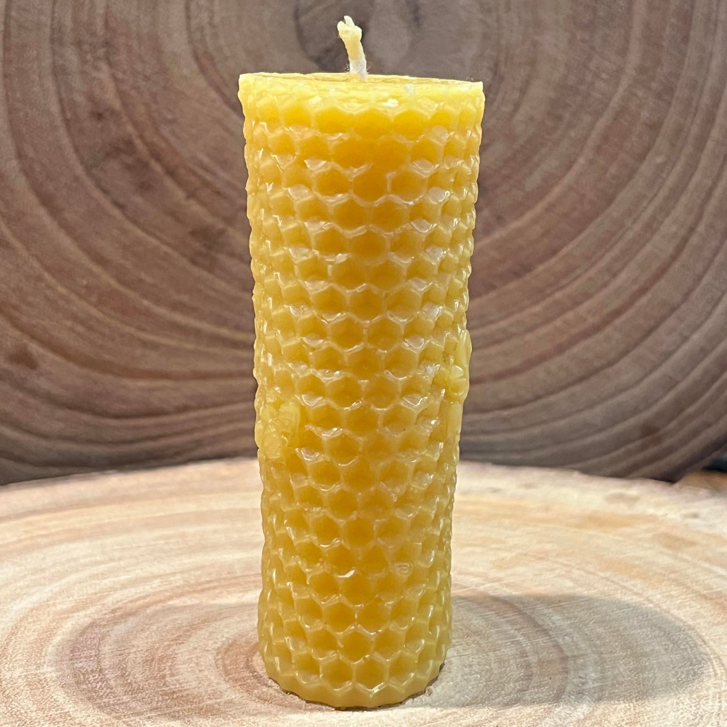 The side of a yellow beeswax candle with honeycomb effect and small bee details