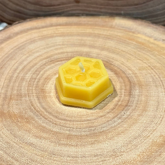 A hexagonal beeswax tea light candle with honeycomb effect on a wooden surface 
