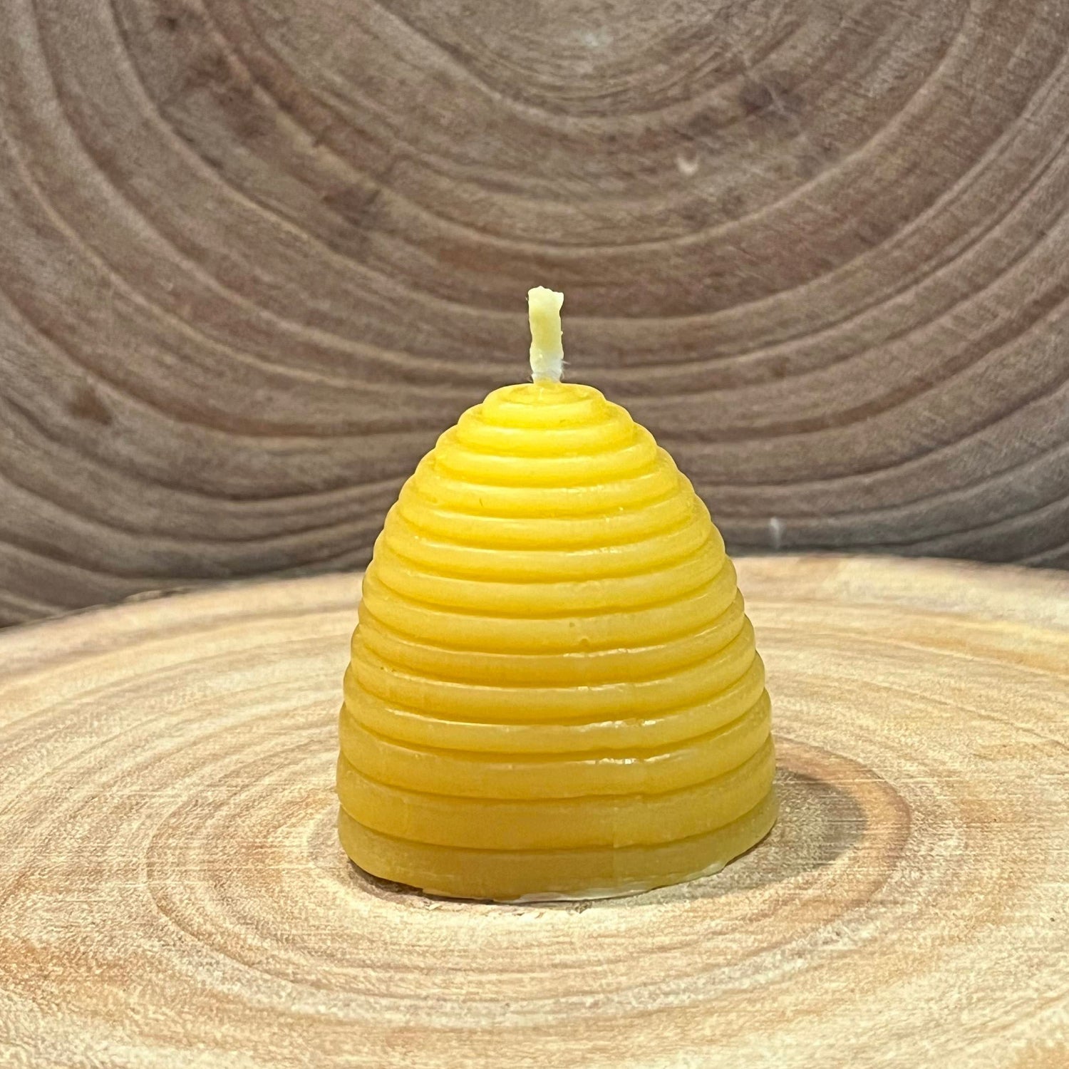 The back of a yellow skep beehive-shaped beeswax candle